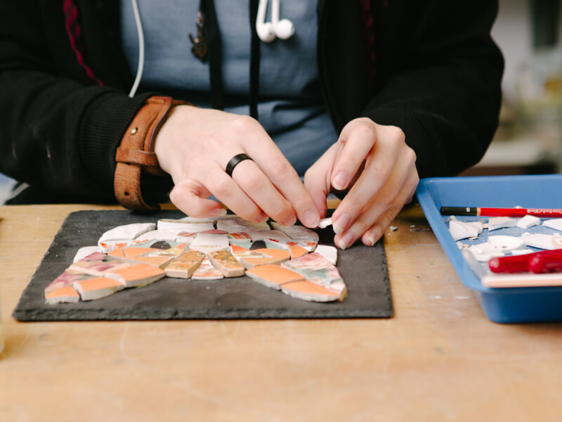 Close up of a person arranging a mosaic depicting a cat